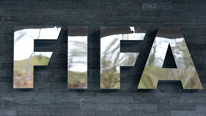 Large reflective metal letters spelling 'FIEA' mounted on a dark stone wall.