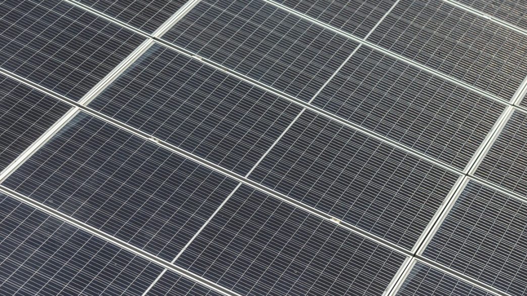 Close-up view of dark blue solar panels arranged in a grid, forming a large solar array.