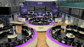 Modern trading floor with curved purple desks, numerous computer terminals, and large Siemens Energy display boards.