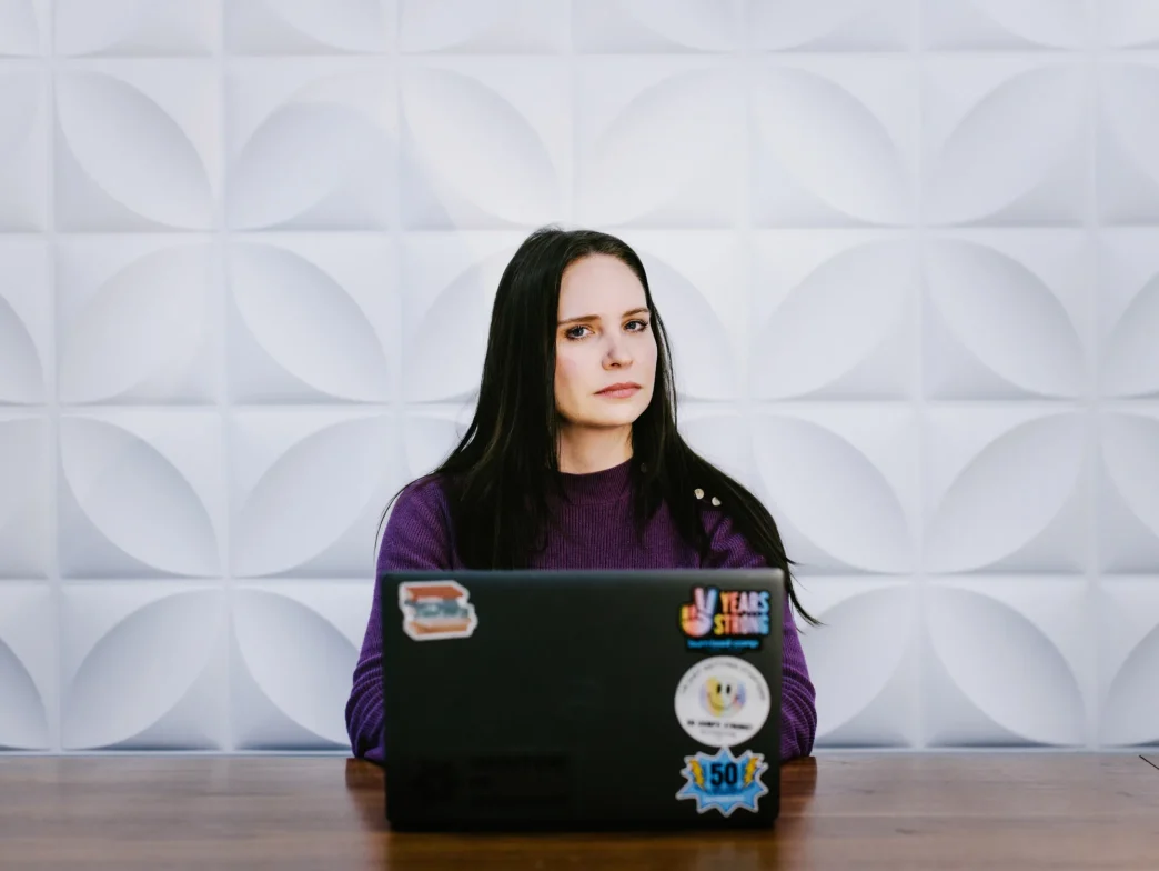 A ransomware negotiator sitting behind a laptop covered in stickers