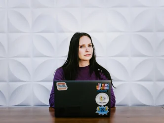 A ransomware negotiator sitting behind a laptop covered in stickers